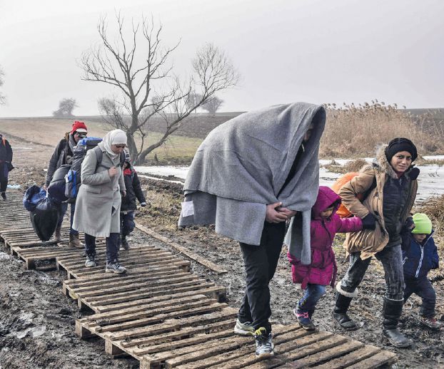 Migrants and refugees walk through a field after crossing into Serbia via the Macedonian border near the village of Miratovac on January 27, 2016. More than a million people headed to Europe in search of new lives last year, most of them refugees fleeing conflict in Syria, Iraq and Afghanistan in the continent's worst migration crisis since World War II. The onset of winter does not appear to have deterred the migrants. / AFP / ARMEND NIMANI