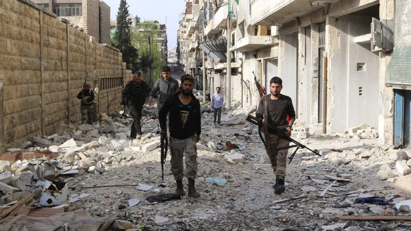 Free Syrian Army fighters walk with their weapons along a damaged street in Bustan al-Basha district in Aleppo